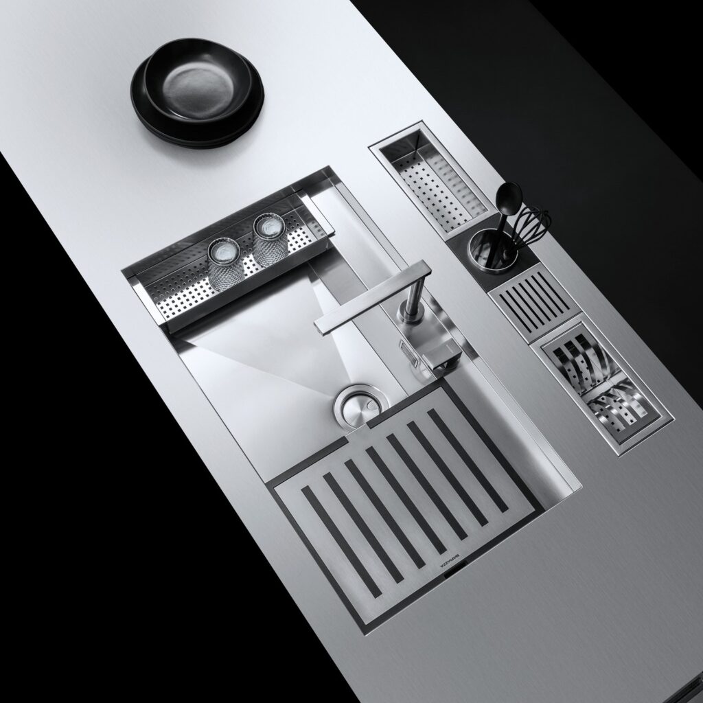 Stainless steel Barazza kitchen sink with integrated Barazza accessories, including a colander, drying rack, and cutting board.