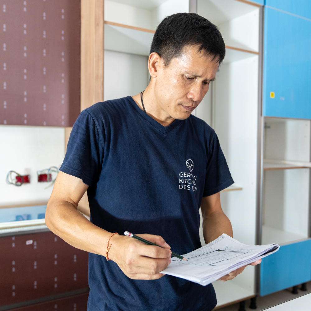 A German Kitchen Design installation manager in uniform reviews blueprints in a kitchen being installed.