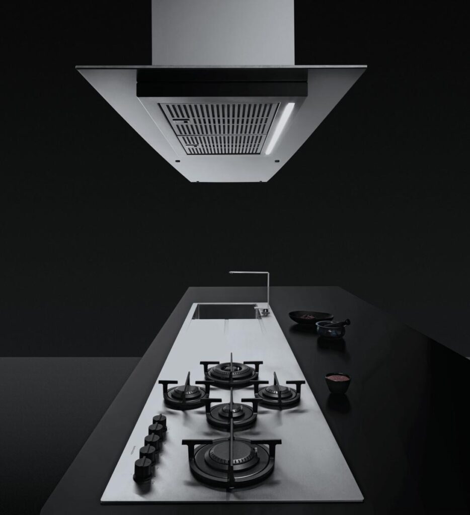 Modern black and silver Barazza range hood above a gas Barazza cooktop on a dark countertop.
