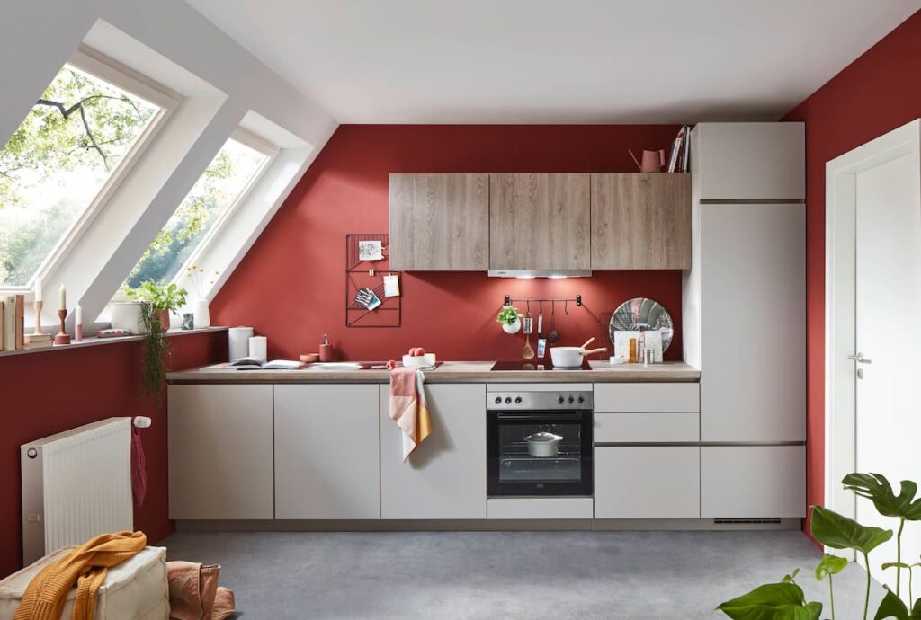 Attic kitchen design with bold red walls, wood accents, and skylights, providing unique kitchen interior design ideas for small spaces.