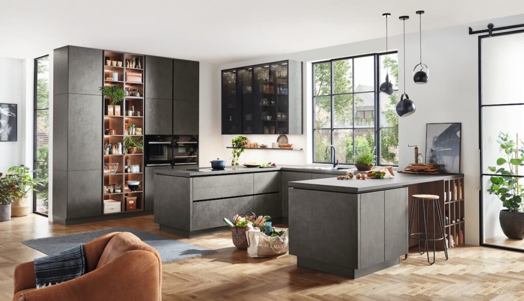 A modern kitchen with dark cabinets and large windows, highlighting eco design with natural light and energy-efficient layout.