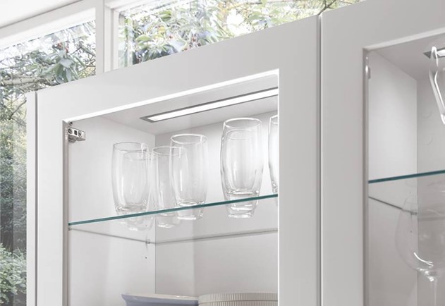 A bright, minimalist white kitchen with integrated appliances, showcasing the clean lines and reflective surfaces often achieved when selecting the best material for kitchen cabinets.