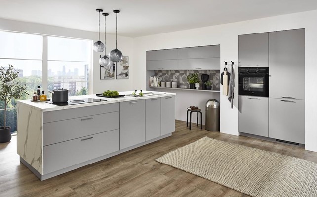 This design features a light gray island with a marble countertop, complemented by patterned backsplash tiles in a similar tonal range.