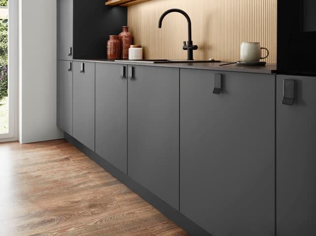 Stylish dark grey kitchen cabinets with a gold backsplash. When considering how much to spend on a kitchen, explore various styles and material combinations to find the right balance for your budget.