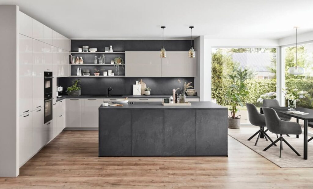 A sleek and modern kitchen featuring a dark stone island with a matching kitchen top, surrounded by warm wooden flooring.